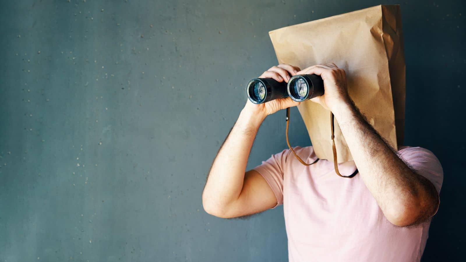 Man with paper bag over his head and holding a pair of binoculars